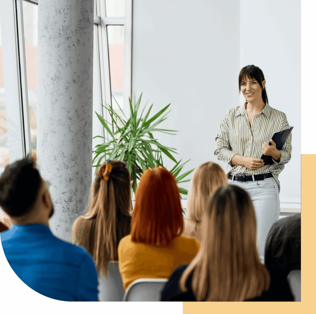 Woman presenting to seated audience in room.