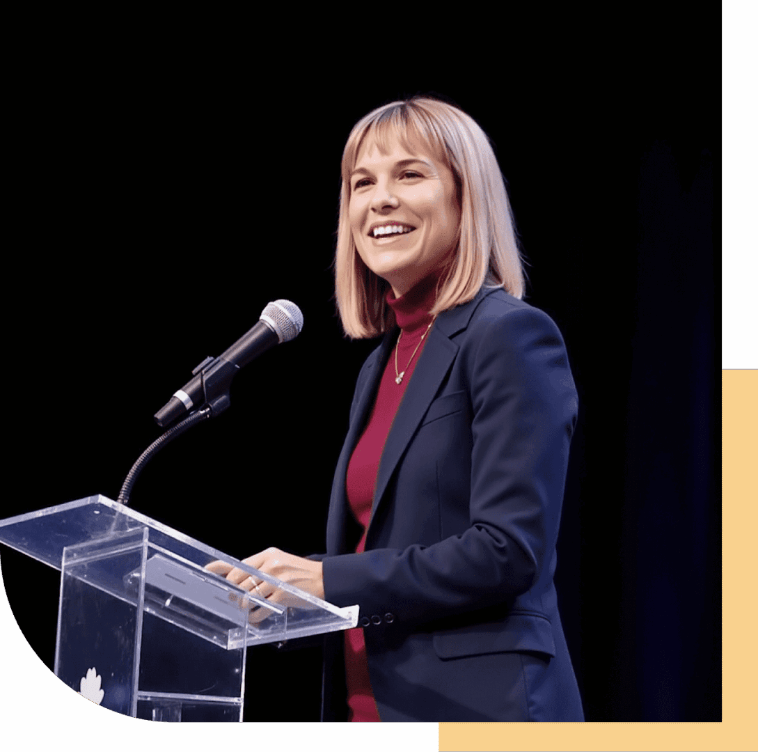Woman smiling while speaking at a podium with a microphone.